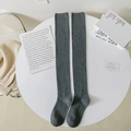 Calze sopra il ginocchio in maglia grigio scuro con polsini a costine su tavolo bianco - Taglia unica / grigio scuro