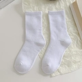 White ribbed cotton crew socks with vertical knit pattern in a minimalist lifestyle setting - Solid White