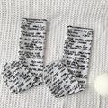 White mid-calf socks with black handwritten cursive prints on waffle fabric background - White