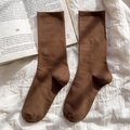 Deep brown cotton mid-calf socks with ribbed cuffs shown on a minimalist cream fabric - One Size / Dark Coffee