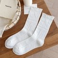 Weiße Baumwollsocken mit Lochmustern und Rüschenbündchen auf einem Holztisch - Einheitsgröße / Weiß