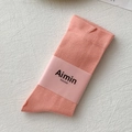 Close-up of salmon pink cotton socks with fine knit texture and branded paper wrap - One Size / Pink