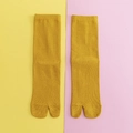 Senfgelbe gestrickte Tabi-Socken mit Zwei-Zehen-Design und Rippstruktur auf zweifarbigem Grund - Einheitsgröße / Gelb