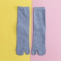 Light grey knitted Tabi socks with two-toe split design on a colorful background - One Size / Blue