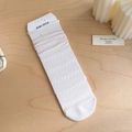 Witte kanten sokken met ruches en KIKI SOX-label op een lichte houten ondergrond - Wit - Labelstijl