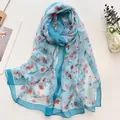 Long summer light blue lotus floral silk scarf shown on white background with magazine - Daisy Blue