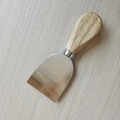 Detail of stainless steel cheese spreader with ergonomic natural wooden handle on wood background - Natural Wood Handle Cheese Spatula