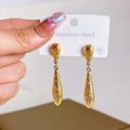 Golden stainless steel teardrop earrings with textured lava finish on a white display card - Textured Hammered Earrings
