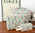 Three-piece floral quilted cotton cosmetic bag set on a wooden table with accessories - Handheld Bag / Nostalgic Flower (Vine)