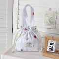Détail du sac à cordon rayé blanc avec broderies florales et logo de lapin sur étiquette - Fleurs brodées colorées