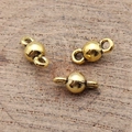 Tre connettori a sfera dorati 5x11mm per gioielli fai da te su sfondo di legno vero - Oro Antico