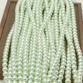Lustrous light teal round faux pearls on a dark wooden tray for jewelry DIY making - Light Green (no. 44) / Approximately 200 Pieces Per Strip 4mm In Size.
