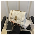 Sac bandoulière blanc matelassé avec fermoir doré rectangulaire sur une chaise moderne - Blanc