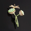 Golden dragonfly lotus brooch with pearls, green enamel, and rhinestones on black background - Lotus Seedpod Dragonfly / Cyan