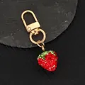 Detailed close-up of handmade sparkling rhinestone strawberry keychain on dark texture - Red