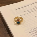 Dettaglio anello vintage dorato con pietre blu e arancioni su un libro - Anello regolabile stile 2