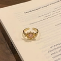Dettaglio dell'anello regolabile in oro con gemma a cuore rosa su un libro - Anello regolabile stile 3