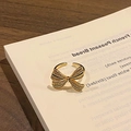 Detailed shot of a gold bow-shaped ring with pavé crystals on a white book surface - Style 8 Adjustable Ring