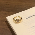 Macro detail of a golden Claddagh ring featuring a heart-shaped zircon on white pages - Style 14 Adjustable Ring