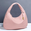 Pink hand-woven leather hobo bag with a gold knot charm in a minimalist studio setting - Pink