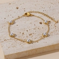 Elegante bracciale a catena dorata con cinque perle bianche su sfondo pietra - Bracciale di Perle Bianche (S552)