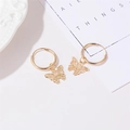 Eleganti orecchini a cerchio con pendente a farfalla traforata in oro su sfondo bianco - Oro