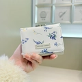 Close-up of floral trifold wallet with vintage heart clasp and textured faux leather - Pastoral Floral Style / Off-white