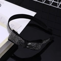 Dettaglio di un cerchietto sottile nero con fiocco di strass scintillanti su base lucida - Cerchietto con fiocco in strass grigio minerale