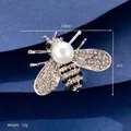 Close-up of a silver bee brooch with sparkling rhinestones and a large pearl center - White K Bee (XD8662-2)