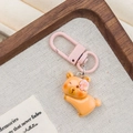 Detail von rosa Karabiner und süßem orangem Bärenanhänger aus Harz auf Textilgewebe - Vorderbeinstreckung