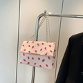 Detail view of pink corduroy shoulder bag featuring red strawberry prints and gold chain - Pink