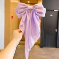 Elegant lavender silk bow hair clip with long streamers held in a warm indoor setting - Light Purple