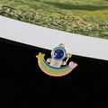 Close-up of cute enamel astronaut charm sitting on rainbow with gold-plated edges - Astronaut Sitting on Rainbow (V)