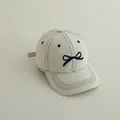 White cotton kids baseball hat featuring navy blue bow embroidery and contrast stitching - Off White