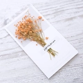 Minimalist greeting card featuring a bundle of dried orange baby's breath on wood background - Orange Baby's Breath Dried Flower Style