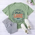 Detail of pea green T-shirt with lake print, 2XL tag, and rustic lifestyle props - S / Olive Green (Black Font)