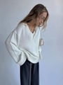 Dettaglio del maglione in maglia bianca con scollo a V e polsini a coste in tessuto - S / Bianco