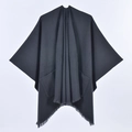 Detail of a black knit poncho featuring side fringe tassels and functional front pockets - Pocket Style Black