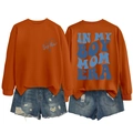 Detail showing the Boy Mom Era graphic print on a bright orange crewneck sweatshirt - Burnt Orange