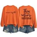 Flat lay of an orange crewneck Mimi Life sweatshirt with ripped denim shorts details - Orange (Black Font)