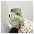 Detail of mint green nylon drawstring bucket bag with slim black rope strap and metal toggle - Green