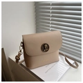 Detail of retro gold cat relief emblem and brand logo on a beige square crossbody bag - Khaki