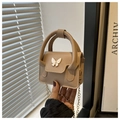 Detailed shot of nude leather mini bag featuring an elegant white butterfly clasp and chain - Khaki