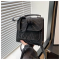 Close-up of black bow backpack with unique wrinkled texture and elegant hand-held strap - Black