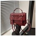 Detail der weinroten Ledertasche mit dekorativen Schleifen und silbernen Herz-Nieten - Rot
