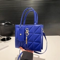 Deep blue quilted square handbag with tassel charm and small pouch on white table - Blue