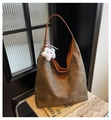 Detalle de bolso hobo gris texturizado con colgante de estrella sobre piedra - Marrón