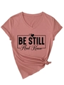 Close-up of pink V-neck t-shirt featuring Be Still And Know text and knot detail - Rose Gold (Black Font)