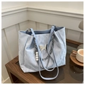 Detail of light blue tote bag with butterfly metal buckle, pearl chain, and pleated texture - Blue