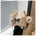 Detalle de bolso cubo blanco con textura plisada y adorno de mariposa plateada - Blanco Con Colgante